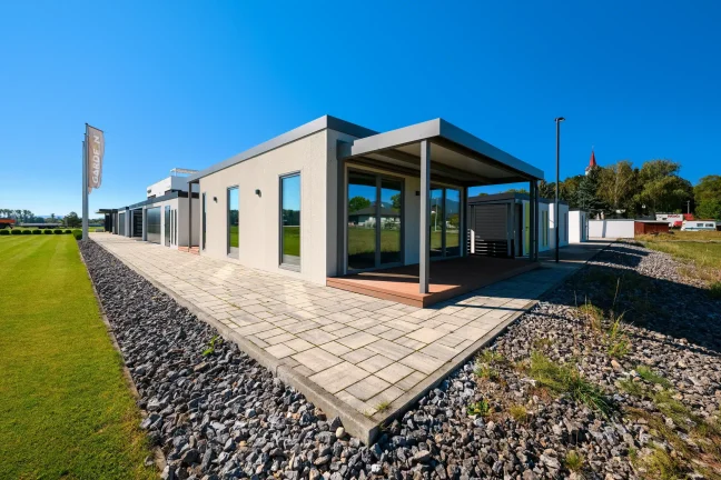 Tiny House mit überdachter Terrasse und gepflastertem Weg entlang des Rasens