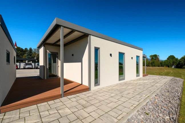Vordere Ecke des Tiny Houses mit überdachter Terrasse und großen Glastüren