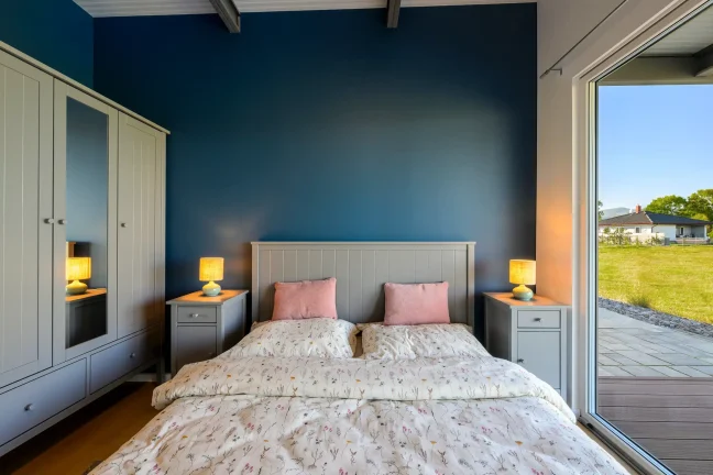 Doppelbett mit Kleiderschrank und großem Fenster zur Terrasse