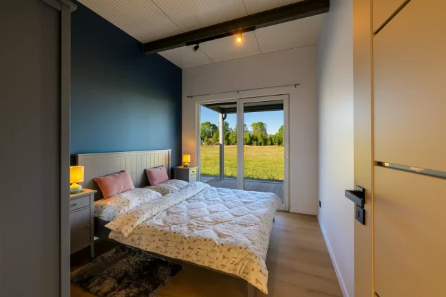 Schlafzimmer des Tiny Houses mit Doppelbett und Blick auf die Terrasse