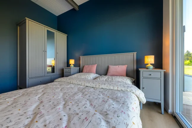 Schlafzimmer mit dunkelblauer Wand, Doppelbett, Nachttischen und Kleiderschrank