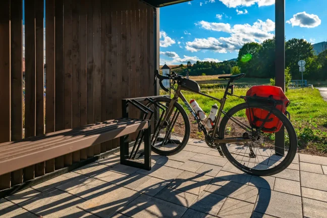 Fahrrad im Ständer neben der Sitzbank unter der Haltestellenüberdachung